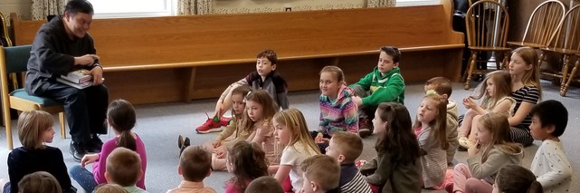 A priest gathered with children after the family friendly Mass.