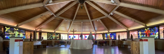 A chapel with a wooden ceiling and stained-glass windows.