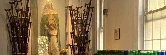 Candle racks beside a statue in the St. Anne Votive Chapel.